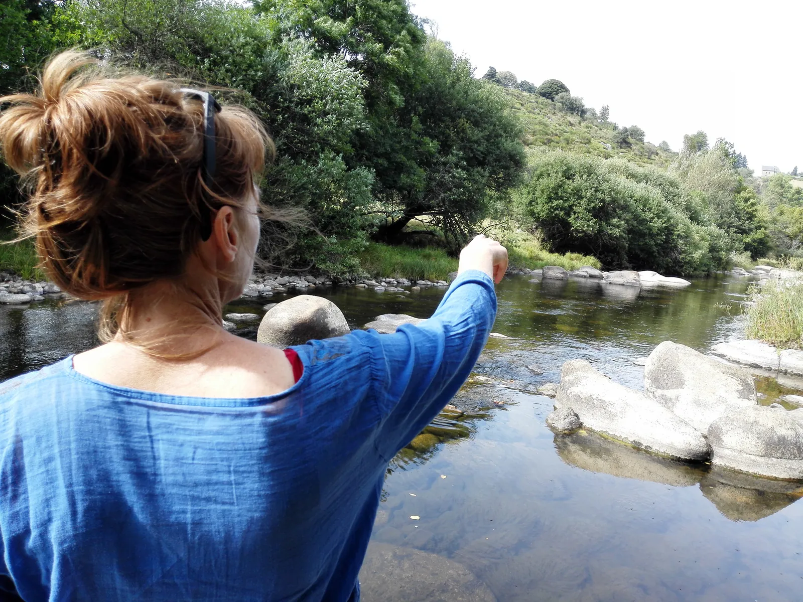 Une femme au bord d'une rivière, le bras tendu