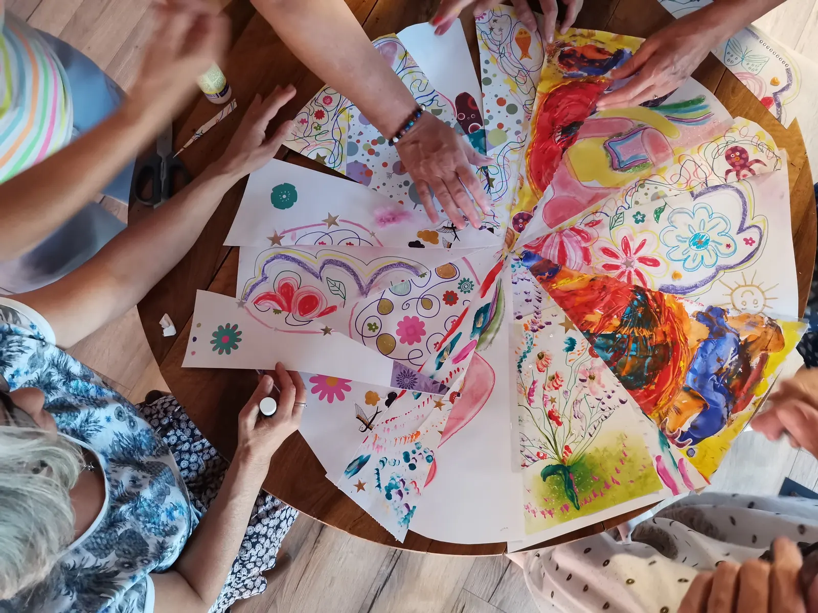 Des mains autour d’un mandala peint à plusieurs