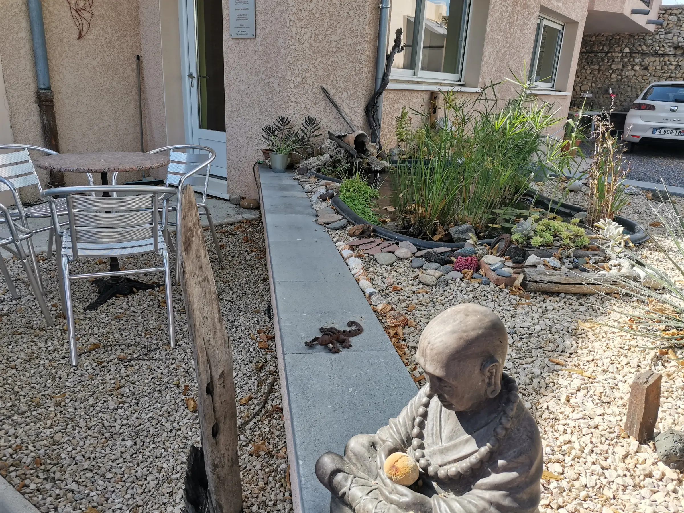La cour d'entrée du centre : le jardin de galets, une statue assise en méditation