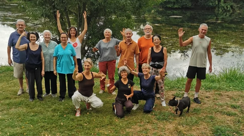 Les élèves de l'école de Tai Chi réunis au bord de l'eau, mains levées, en août 2026