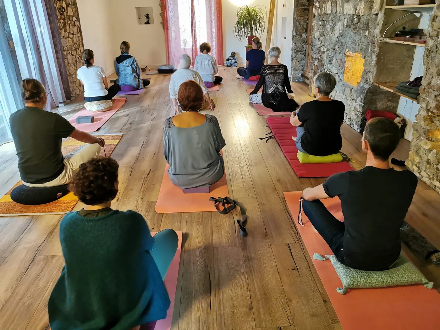 Une séance de méditation dans la salle : les pratiquants assis sur leurs tapis
