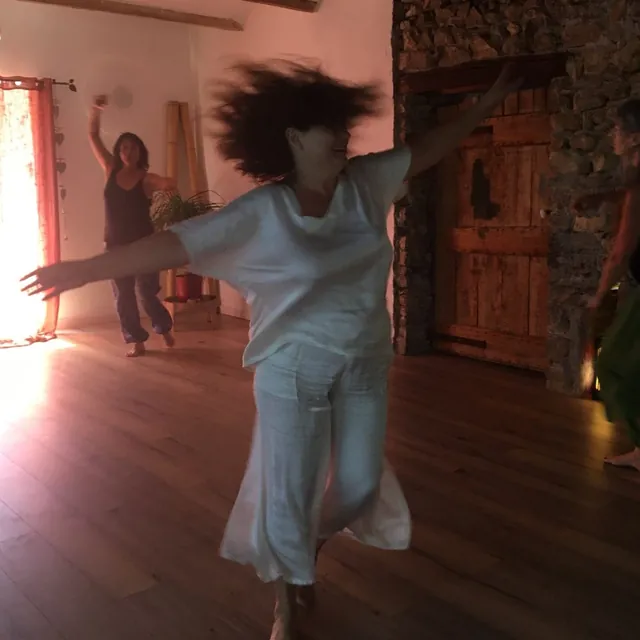Une participante danse, les bras ouverts, dans la salle de l’atelier