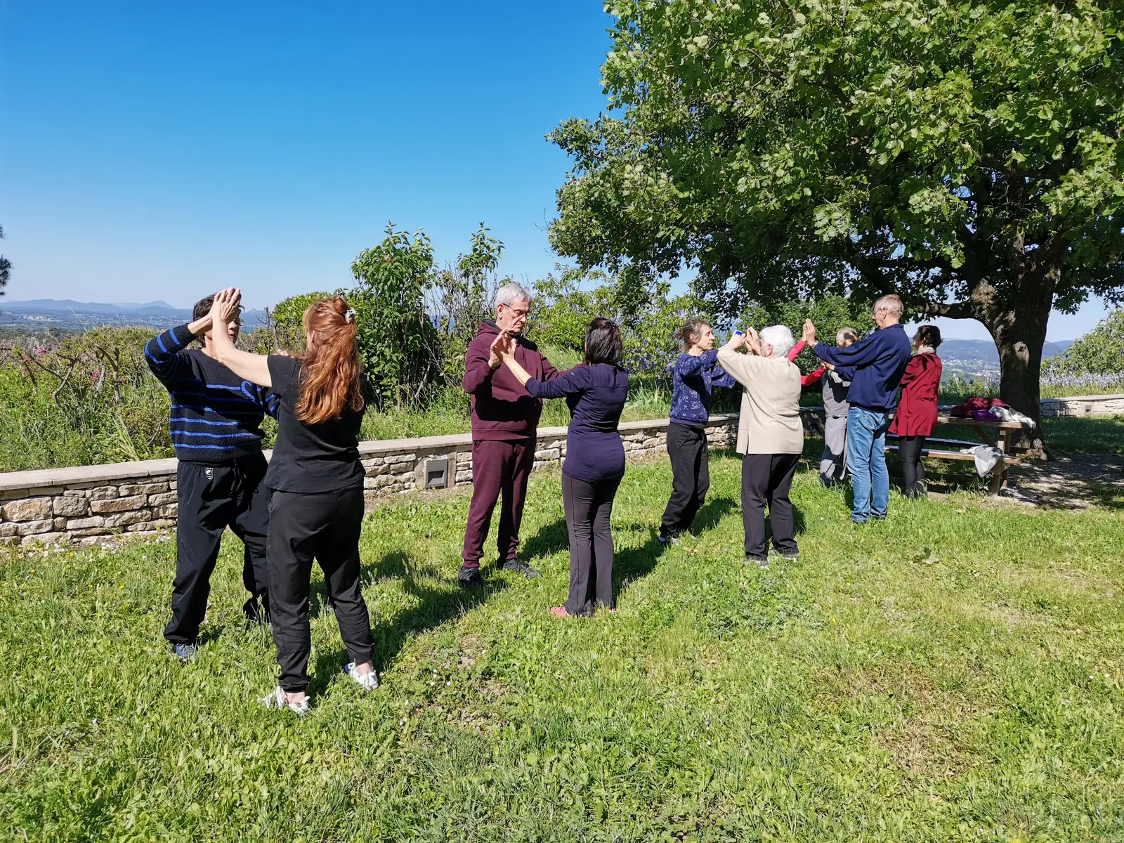 Pratique collective en plein air, au-dessus d'un muret, les collines au fond