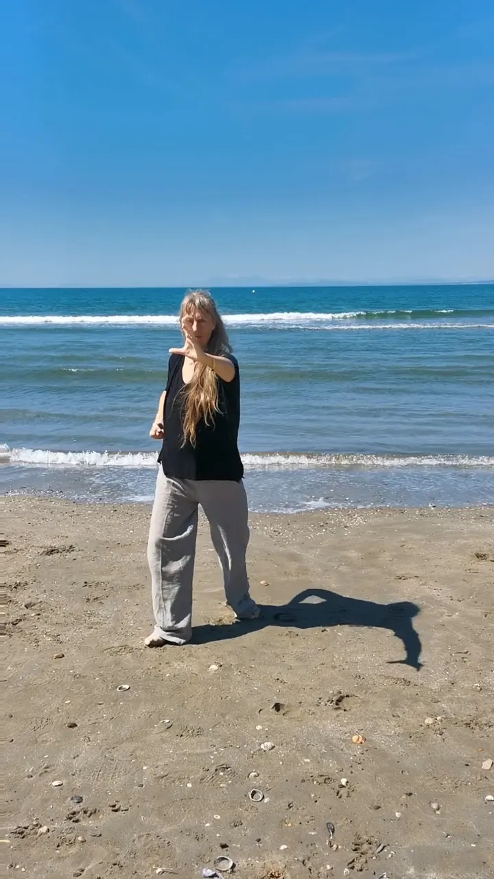 Catherine Mauguin au bord de la mer, premier temps du mouvement : les mains se rassemblent devant